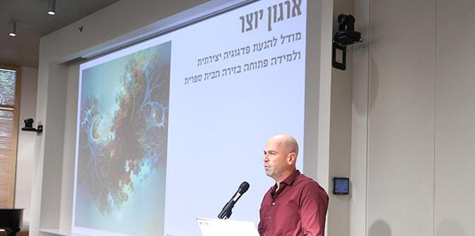 Fellow speaking into a microphone in front of a slide with his topic and poster
